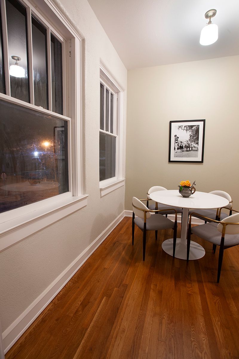 A dining room with a table and chairs and a picture on the wall.
