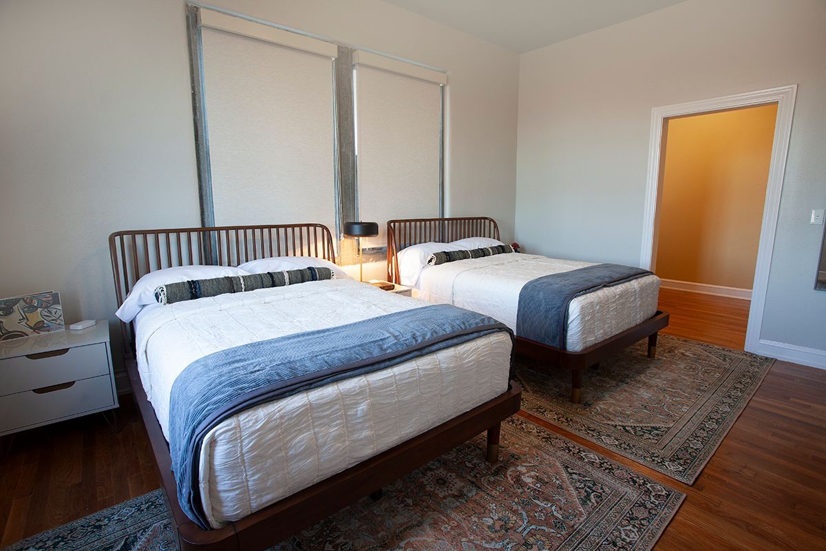 A bedroom with two beds and a rug on the floor.