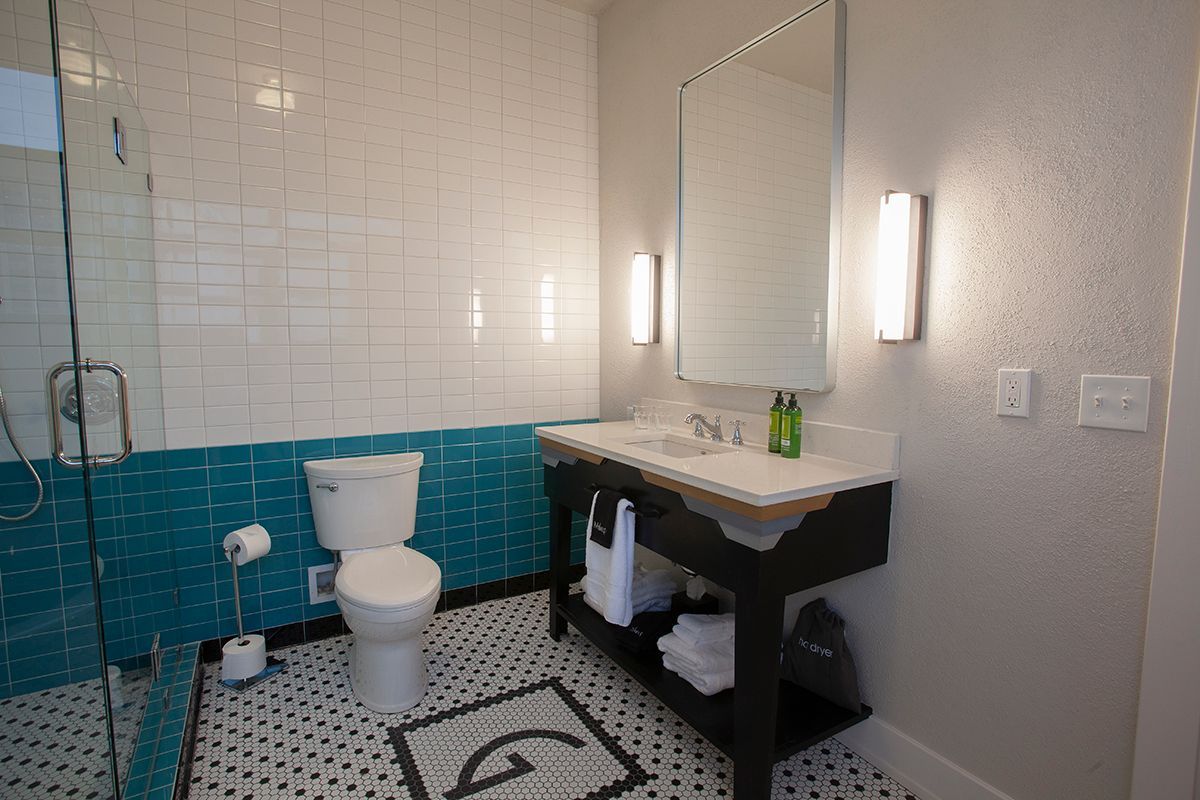 A bathroom with a toilet , sink , mirror and walk in shower.