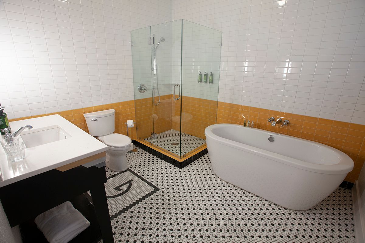 A bathroom with a tub , toilet , sink and shower.