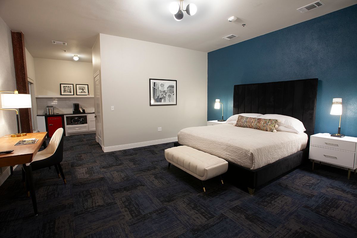 A hotel room with a king size bed and a desk.