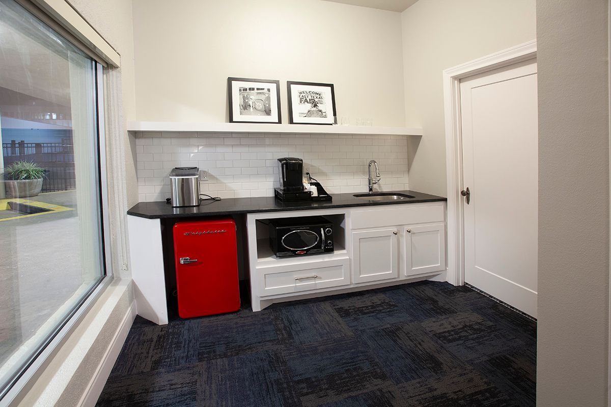A kitchen with a red refrigerator , sink , and microwave.