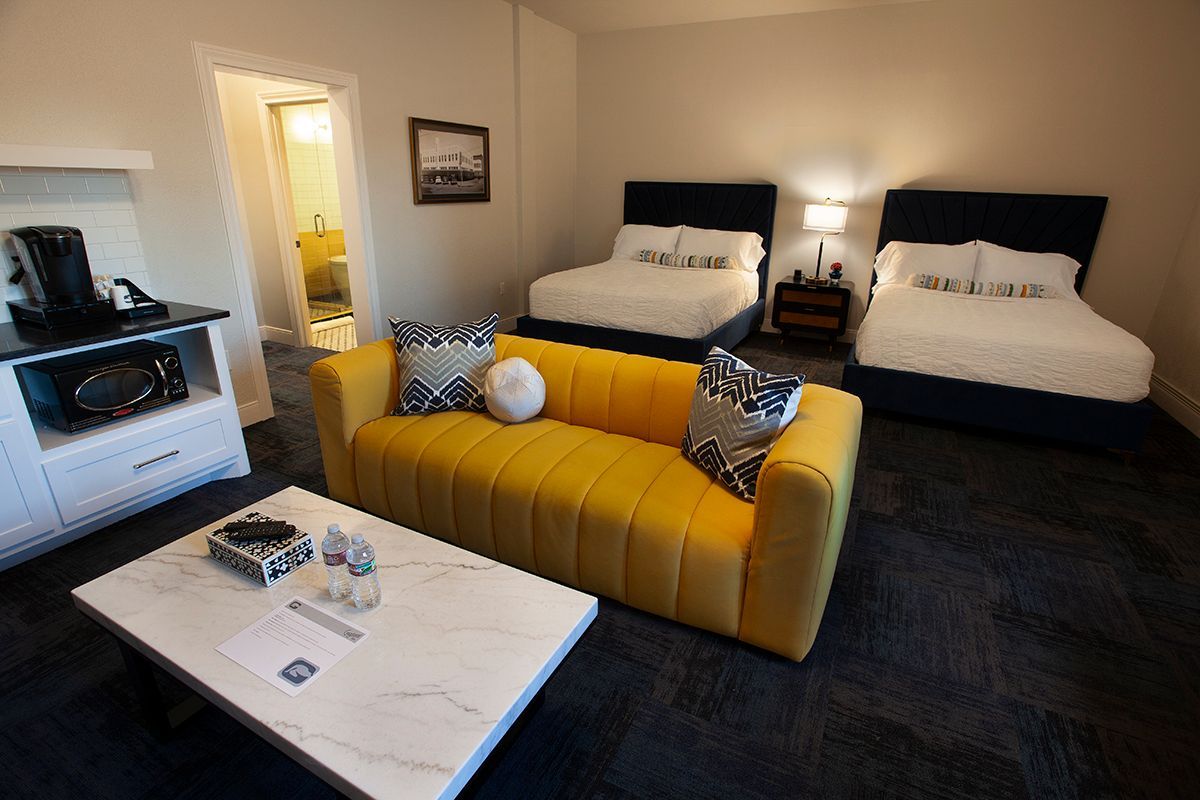 A hotel room with two beds and a yellow couch