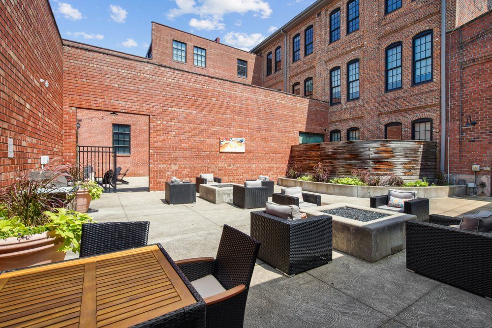 Outdoor patio with brick buildings, seating, and a water feature.