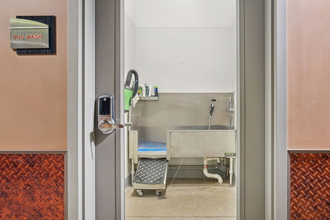 Doorway into a pet grooming room with a stainless steel tub and grooming supplies.