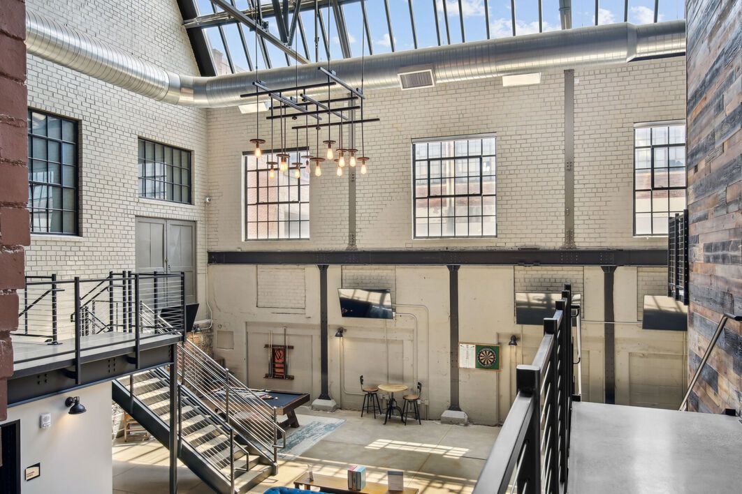 Interior of a brick-walled building with industrial-style windows, skylights, and a staircase.