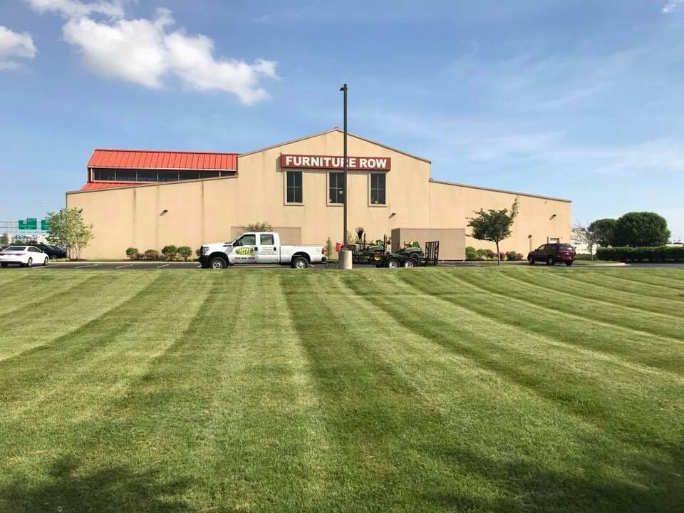 Furniture Row store with a freshly mowed lawn and landscaping truck parked in front.