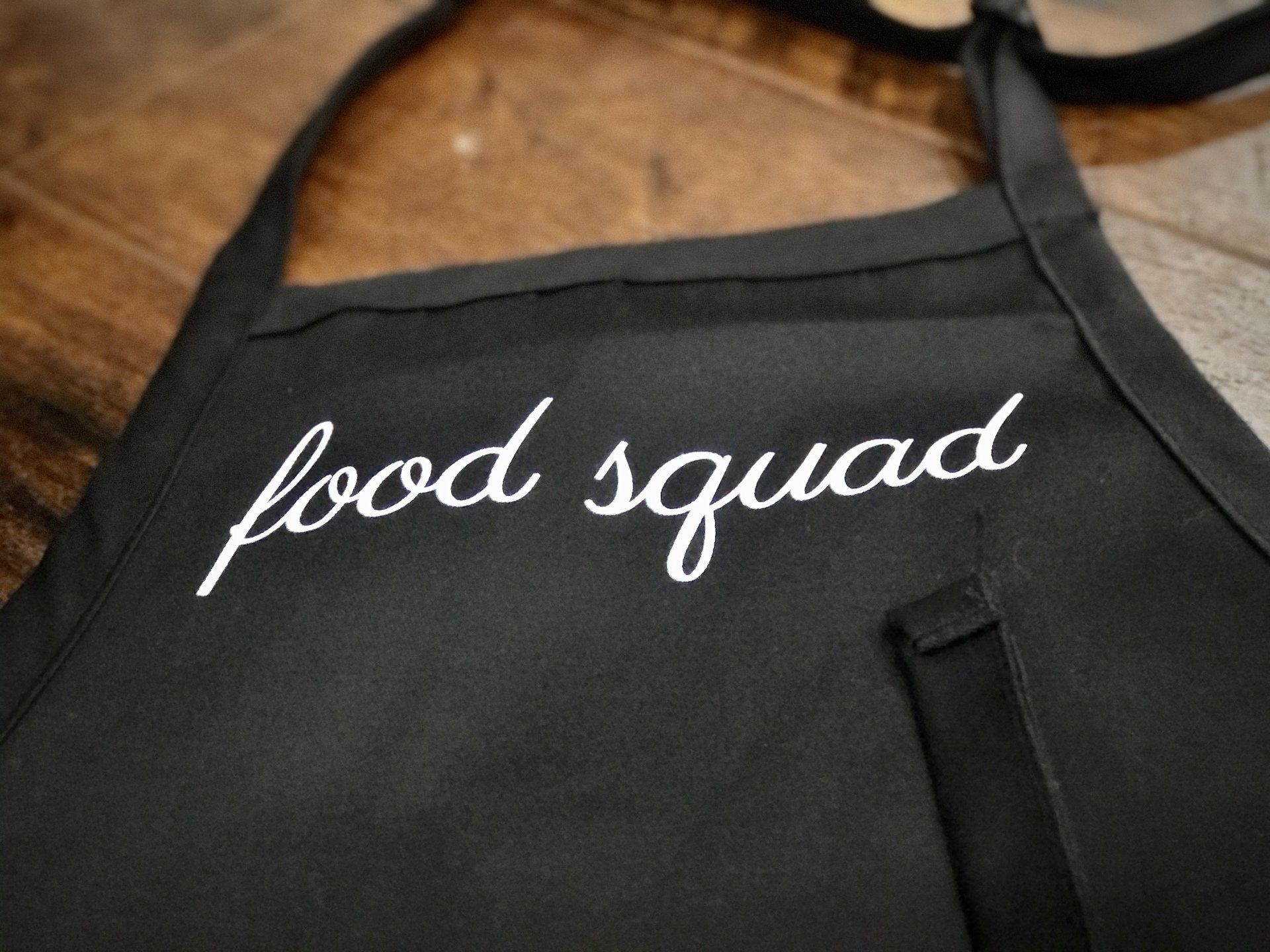 a black apron that says food squad on it