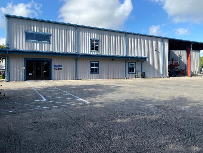 A large metal building with a parking lot in front of it.