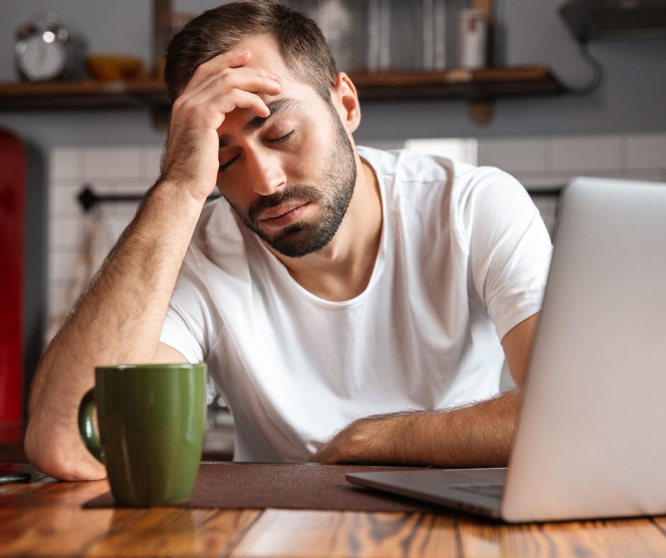 A man is sitting at a table with a laptop and a cup of coffee.