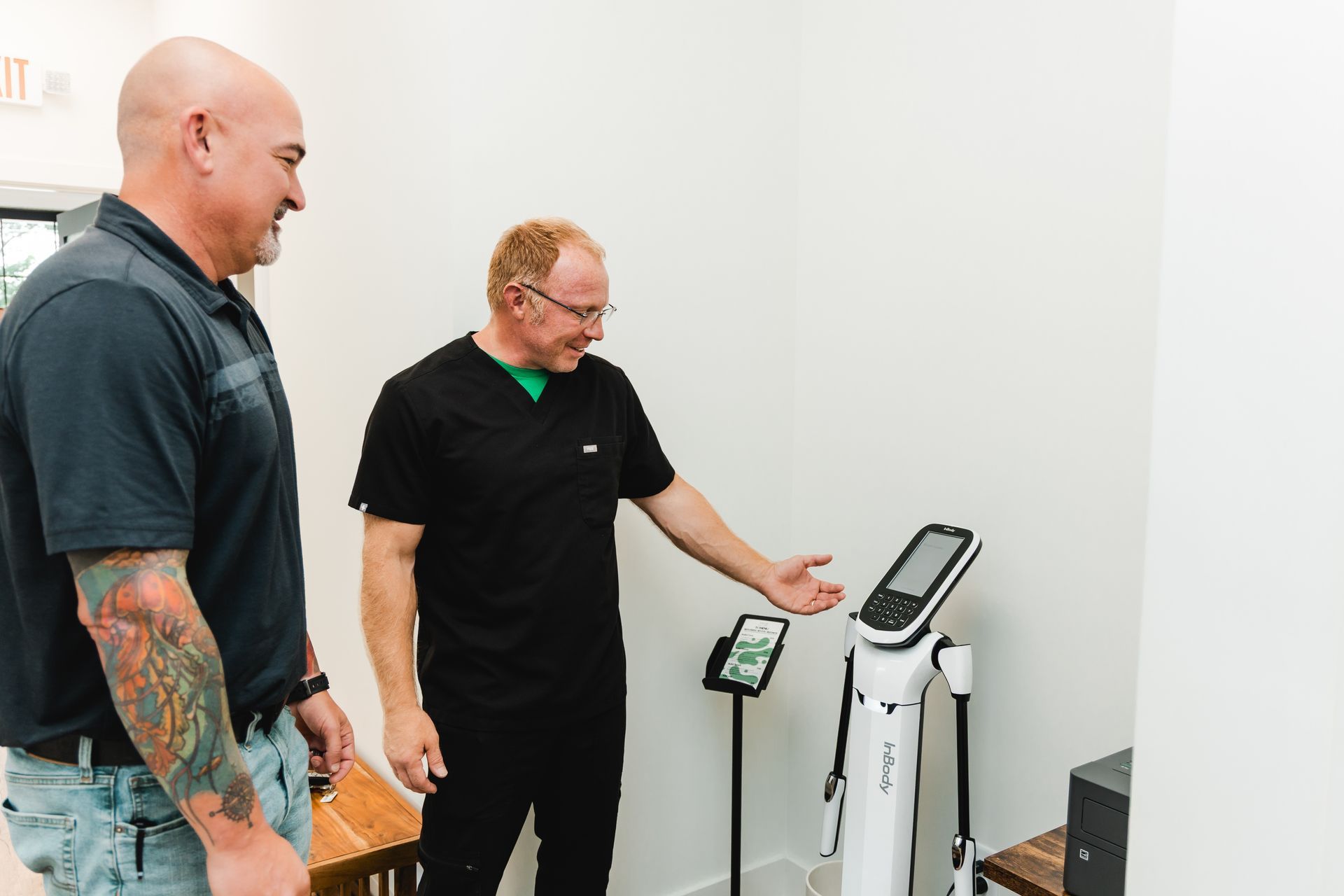 Man and doctor looking at a body composition analyzer in a medical office.