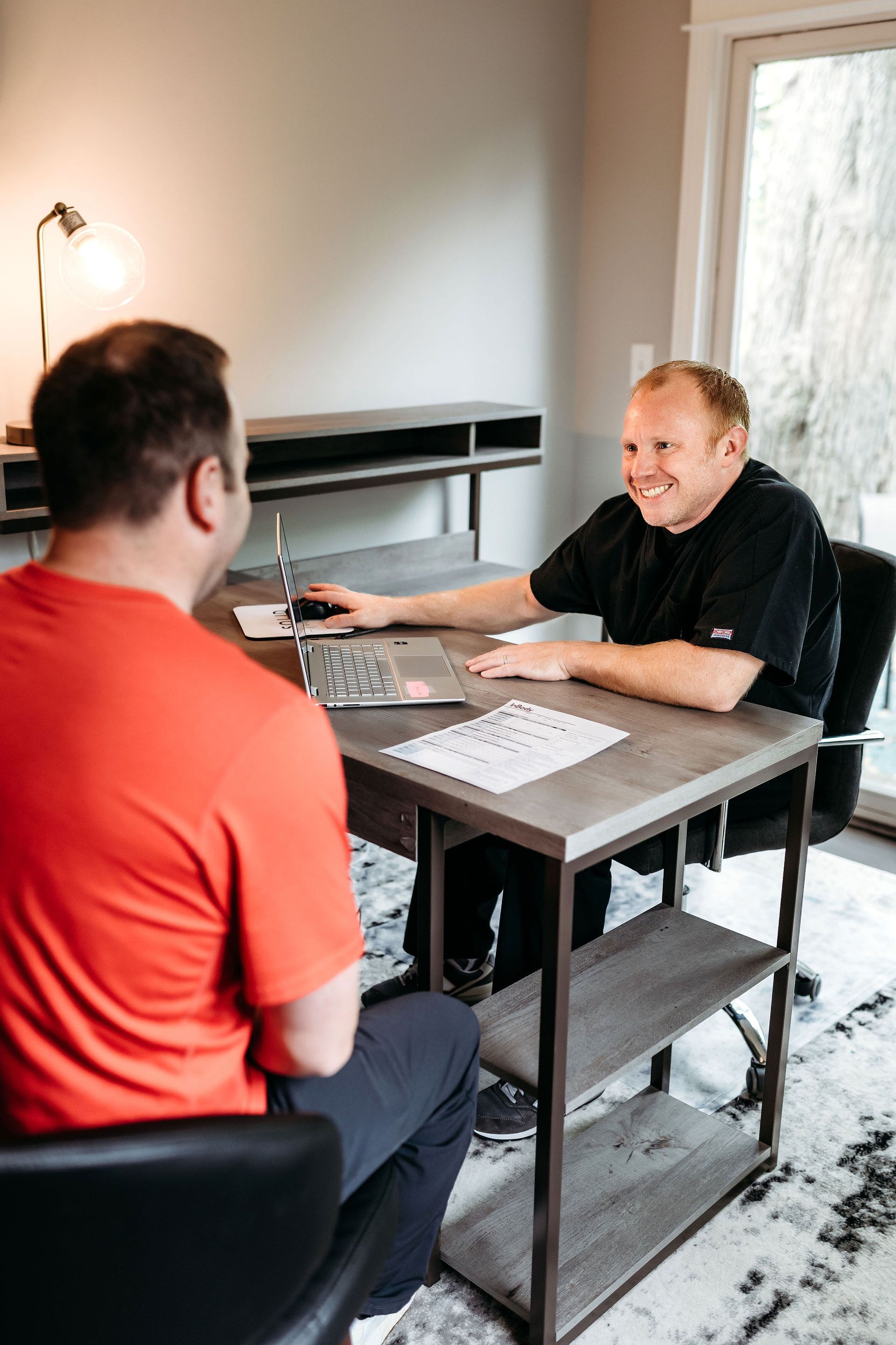 Two men are sitting at a table talking to each other.