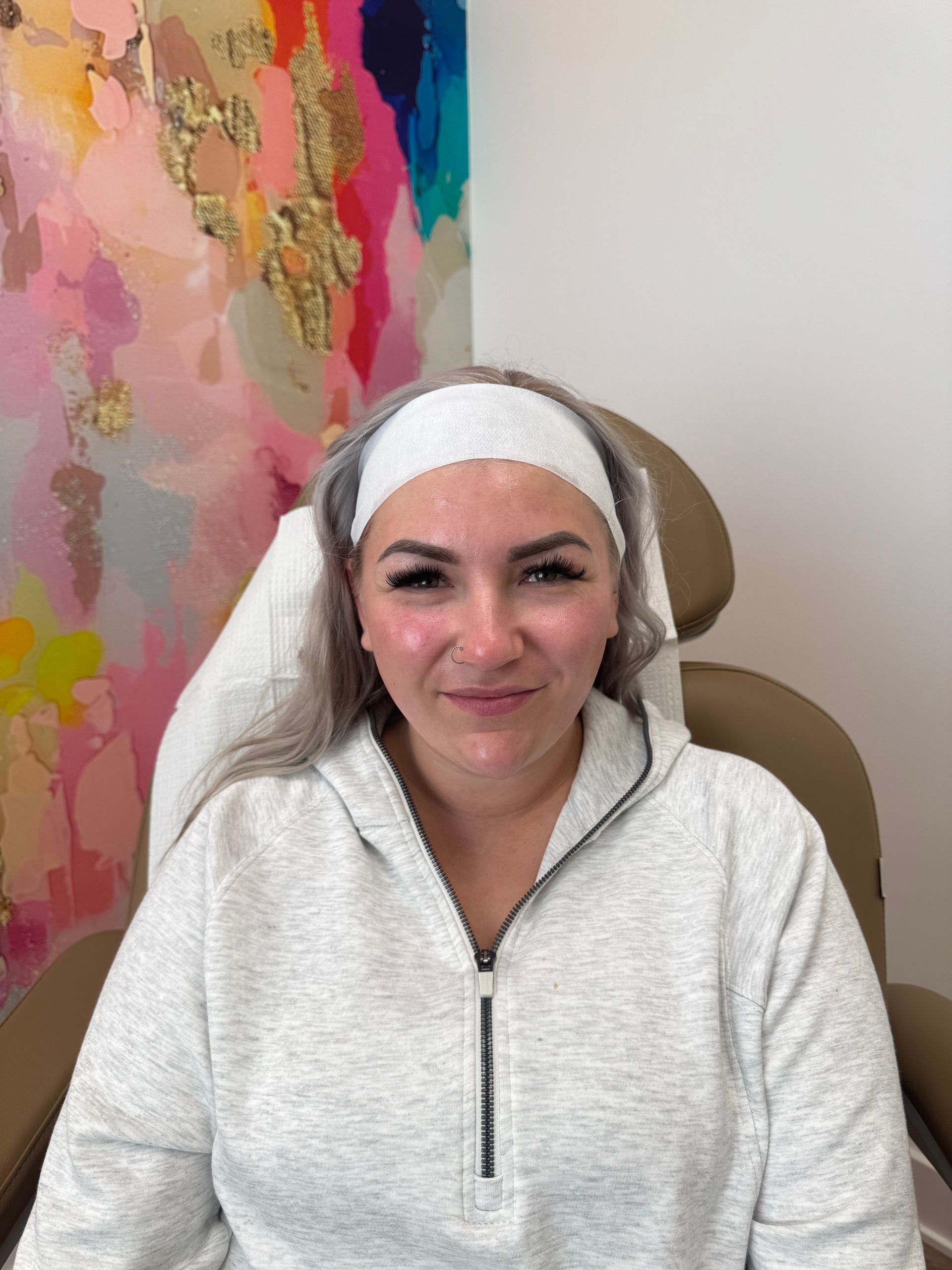 A woman is giving a thumbs up to another woman while sitting in a chair.