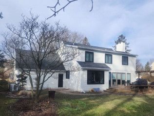 The back of a white house with black windows and a black roof.