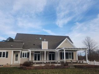 A large house with a large porch and a blue sky in the background.