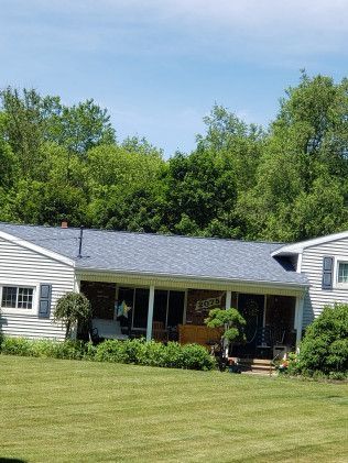 A white house with a blue roof is sitting on top of a lush green field.