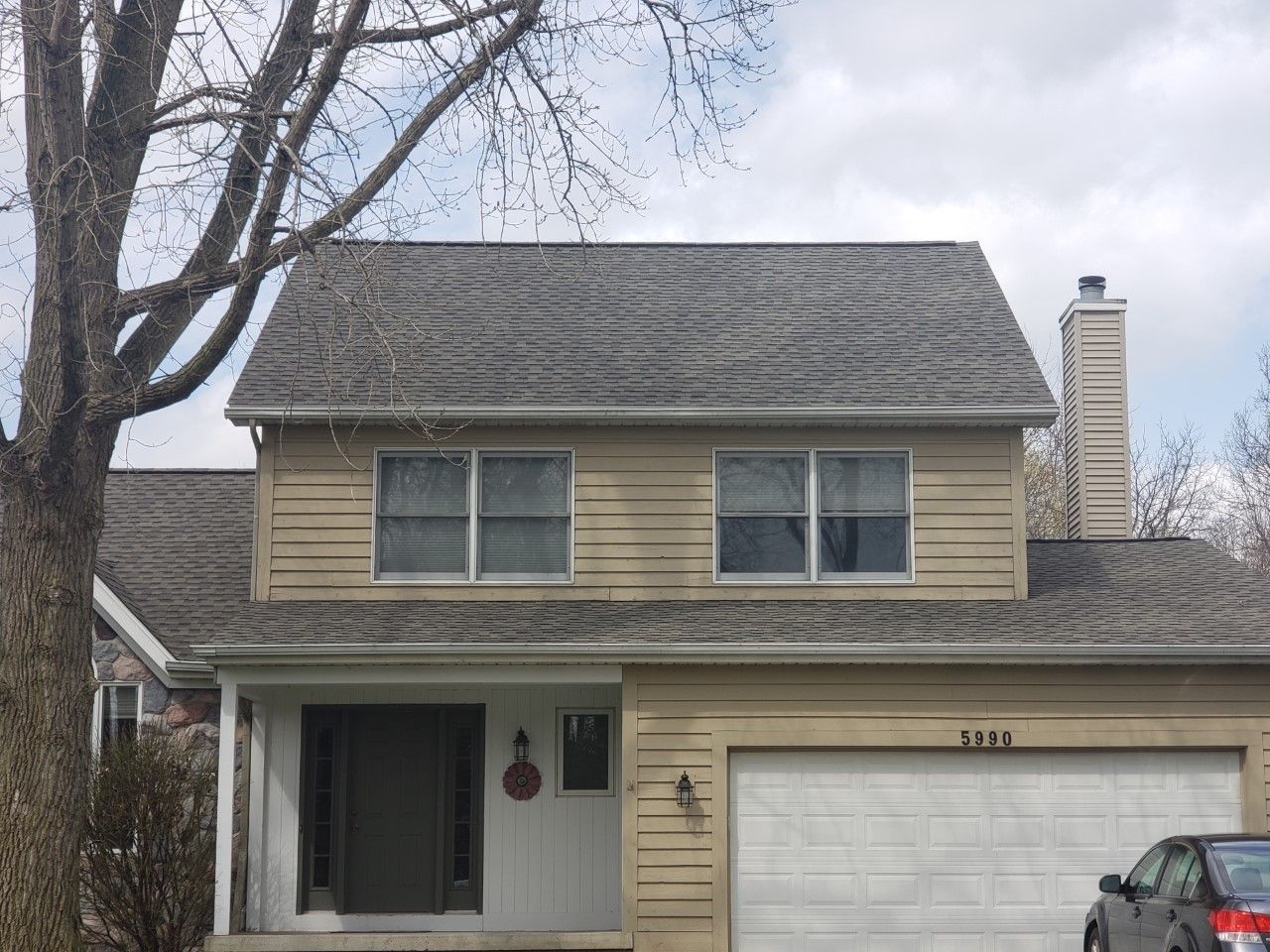 A house with a garage and a car parked in front of it.