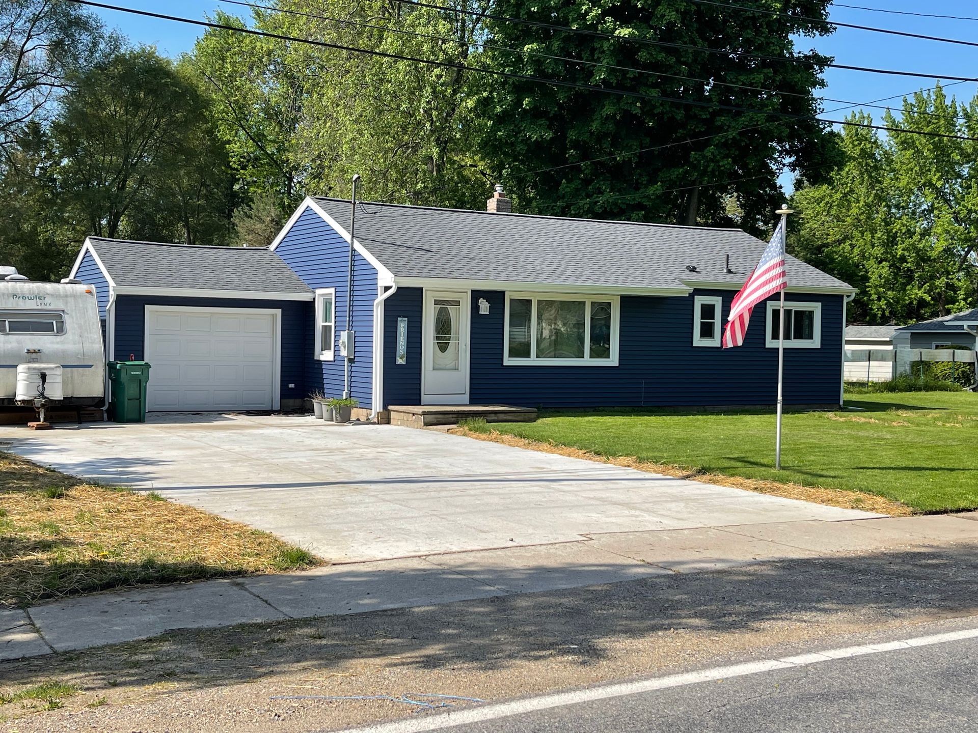 A blue house with a trailer parked in front of it.