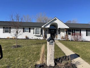 A white house with a black roof and a mailbox in front of it.