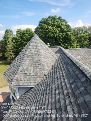 A roof with a cone shaped roof and trees in the background.
