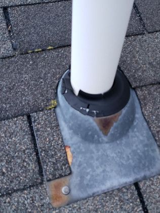 A white pole is attached to a metal base on a brick sidewalk