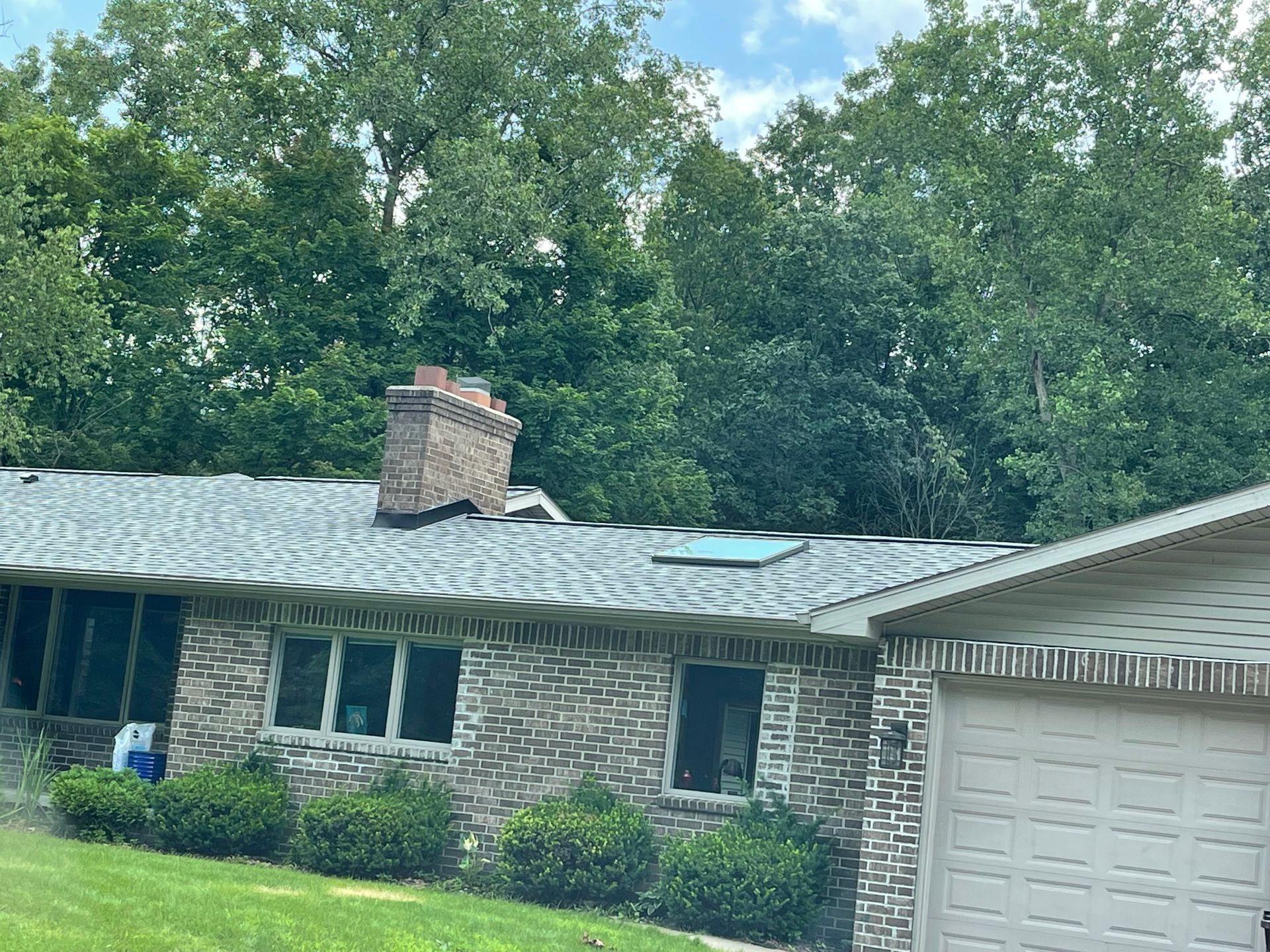 A brick house with a roof that has a skylight on it.