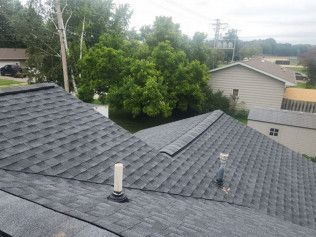 An aerial view of a roof with a chimney and trees in the background.
