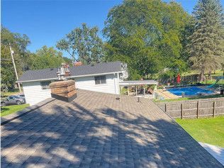 A roof of a house with a chimney and a pool in the backyard.