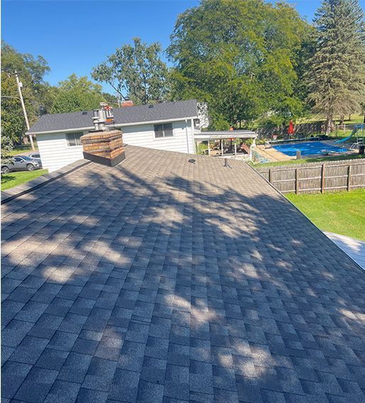 A roof of a house with a chimney and a pool in the backyard.