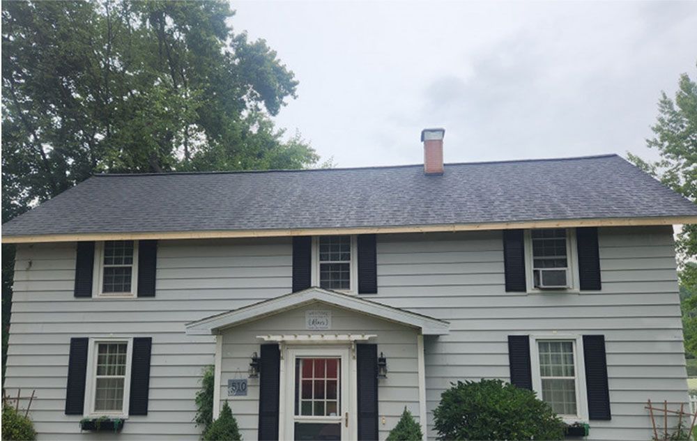 A white house with black shutters and a chimney