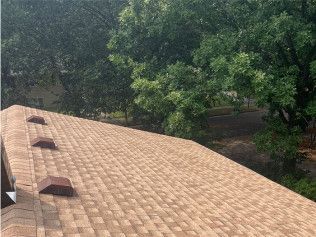 A roof with a lot of shingles on it and trees in the background.