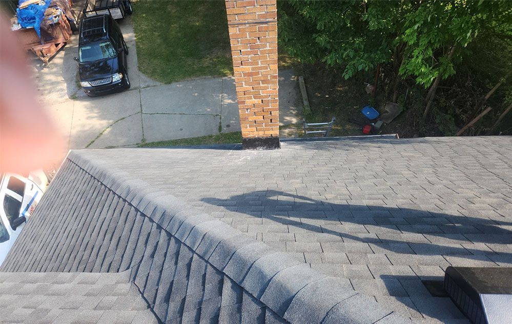 An aerial view of a roof with a chimney and a car parked in the driveway.