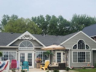 A large house with a patio and umbrella in front of it.