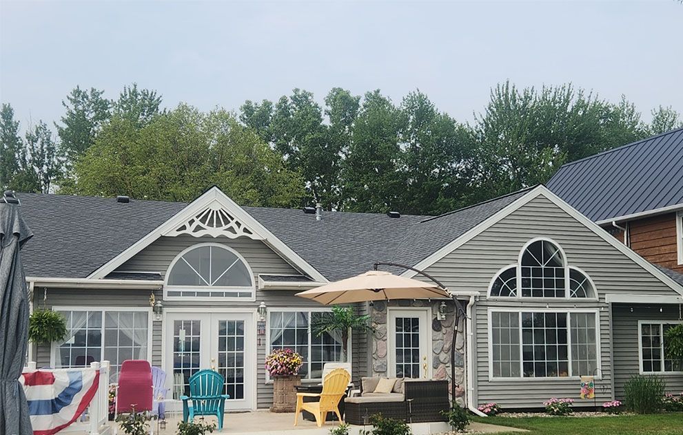 A large house with a patio and umbrella in front of it.