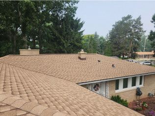 A house with a tan roof and a chimney on top of it.