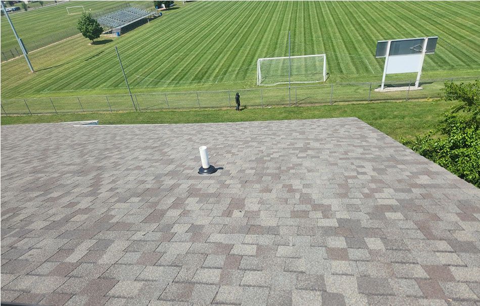 An aerial view of a roof with a soccer field in the background.