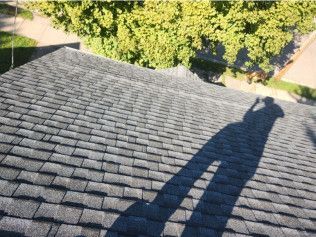 A shadow of a person is cast on the roof of a house.