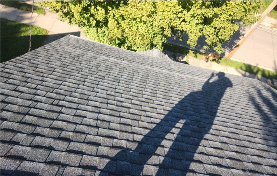 A shadow of a person is cast on the roof of a house