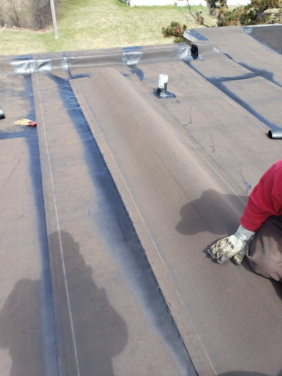 A man in a red shirt is working on a roof