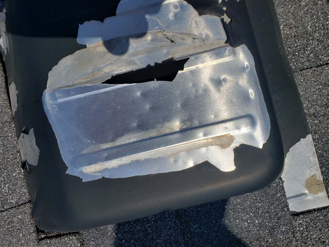 A piece of metal with a hole in it is sitting on a roof.