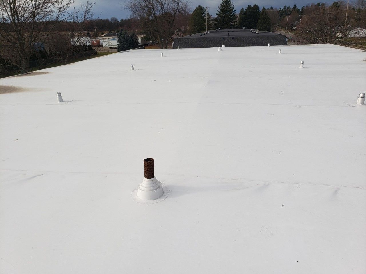 A white roof with a pipe in the middle of it.