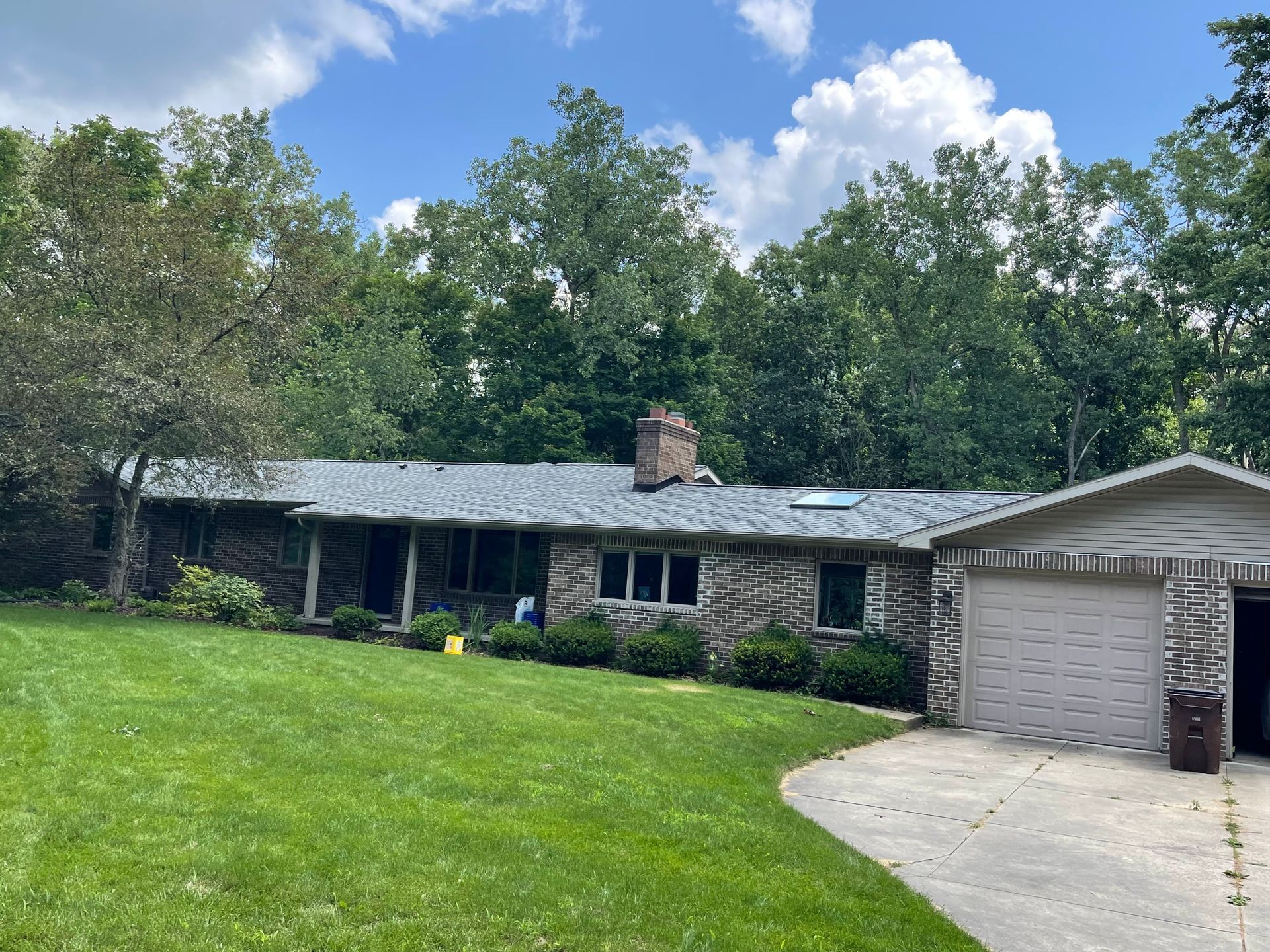 A house with a gray roof and a large lawn in front of it.