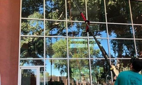 A man is cleaning the windows of a building with a ladder.