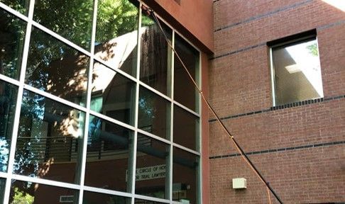 A window cleaner is cleaning the windows of a brick building.