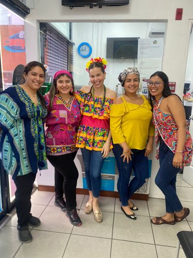 Cinco mujeres con trajes coloridos posan dentro de una oficina bien iluminada.