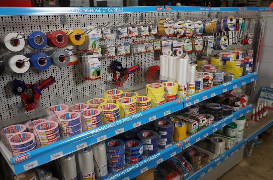 Des étagères présentant divers rubans adhésifs dans une quincaillerie.