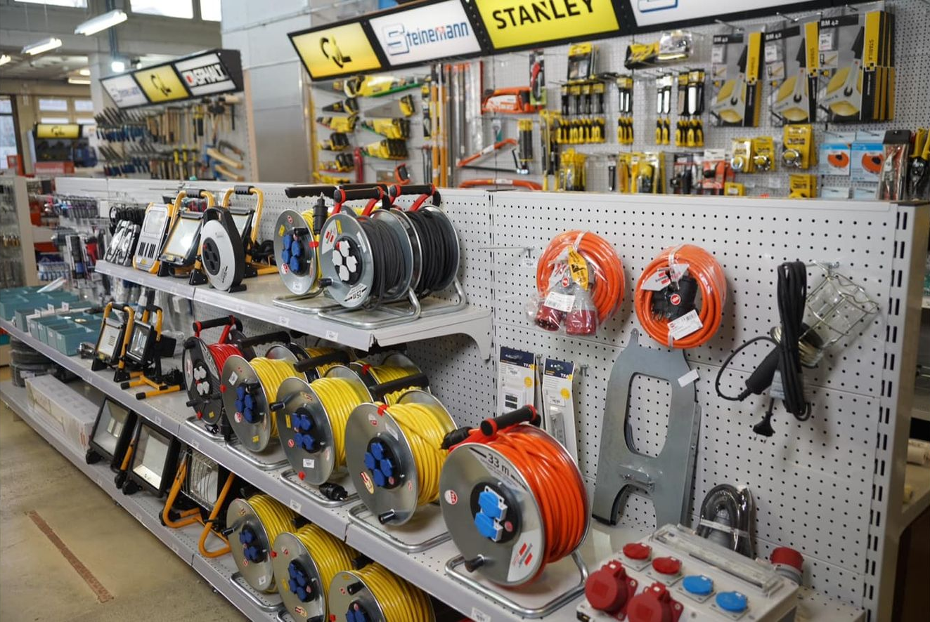 Présentoir de quincaillerie : rallonges électriques, outils et accessoires sur des étagères.