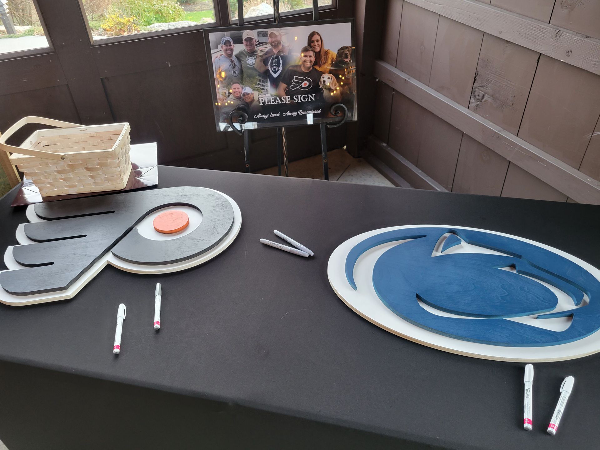 Table with a basket, a photo display, and logos of a hockey team and university for guests to sign.