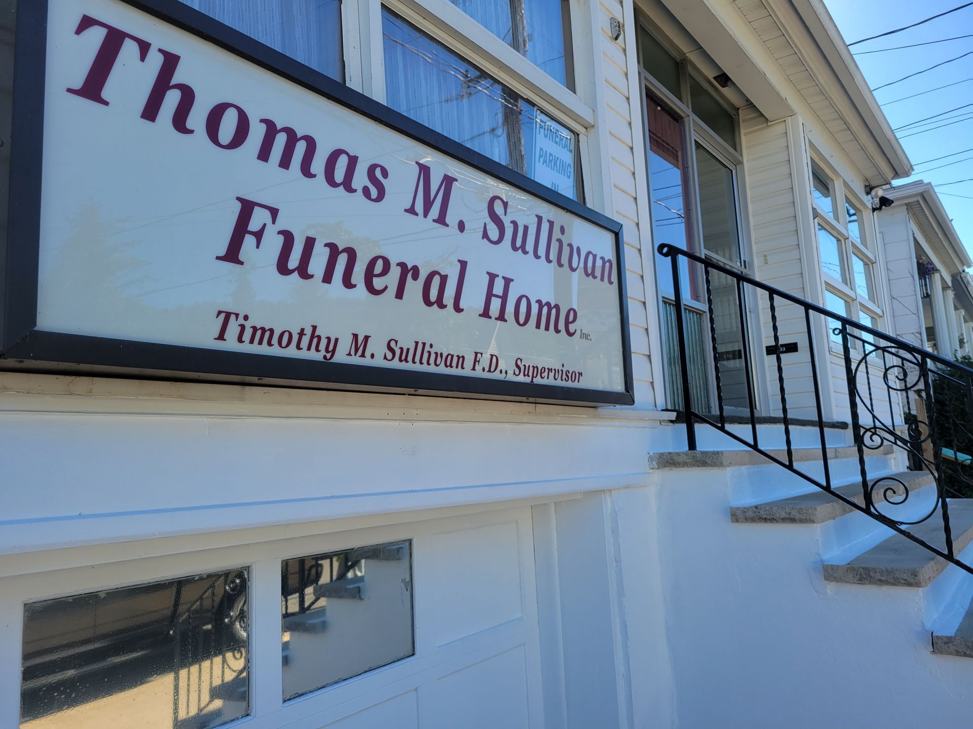 Sign for Thomas M. Sullivan Funeral Home on white building with stairs and black railing.