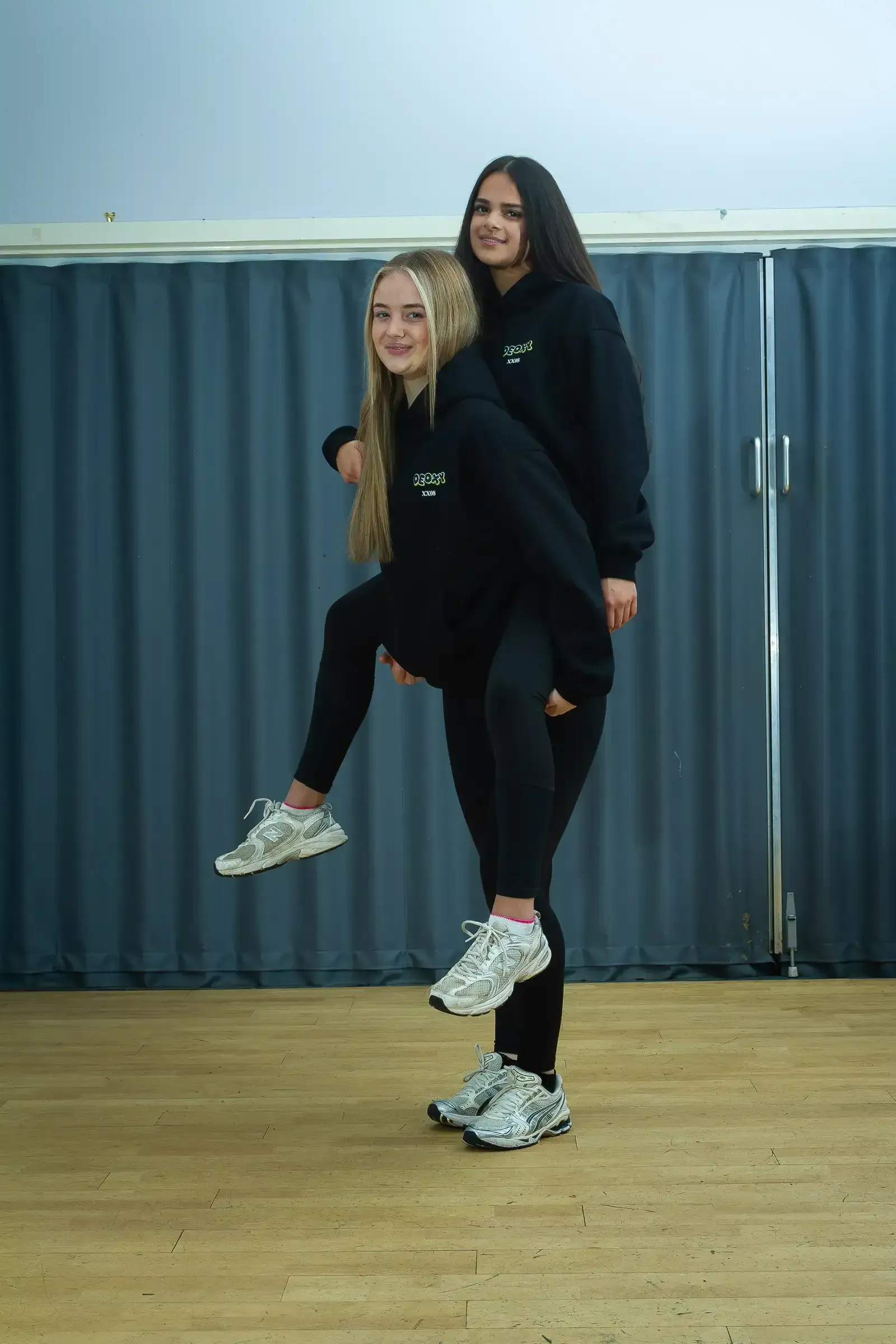 A woman is carrying another woman on her back in a room.